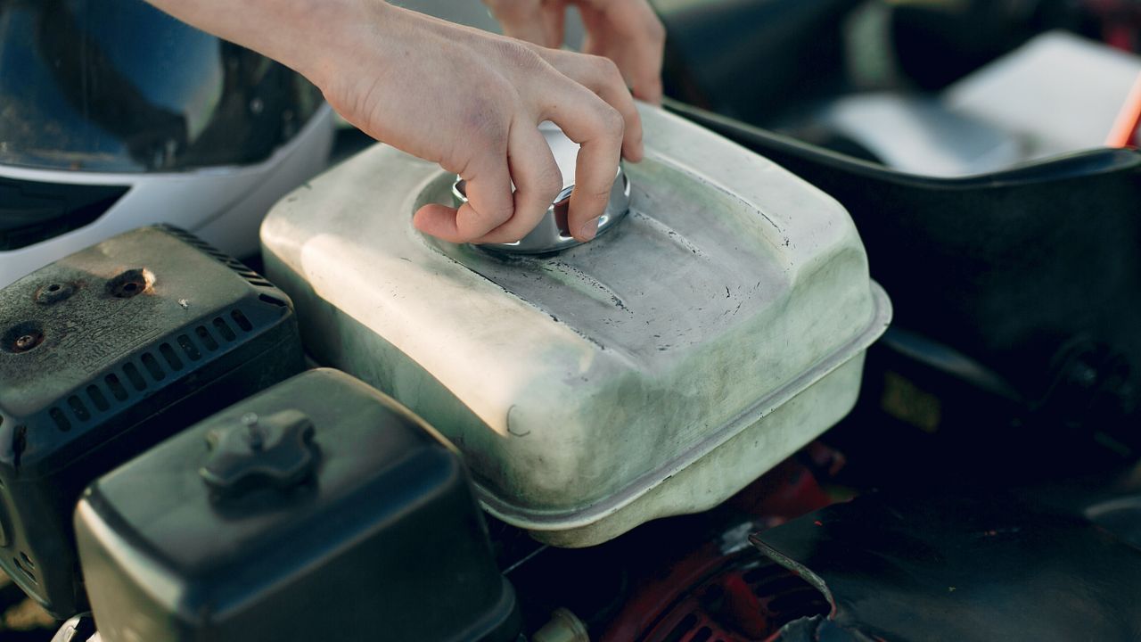 Close-up of a person checking and tightening a gas cap on a vehicle engine as part of routine maintenance.