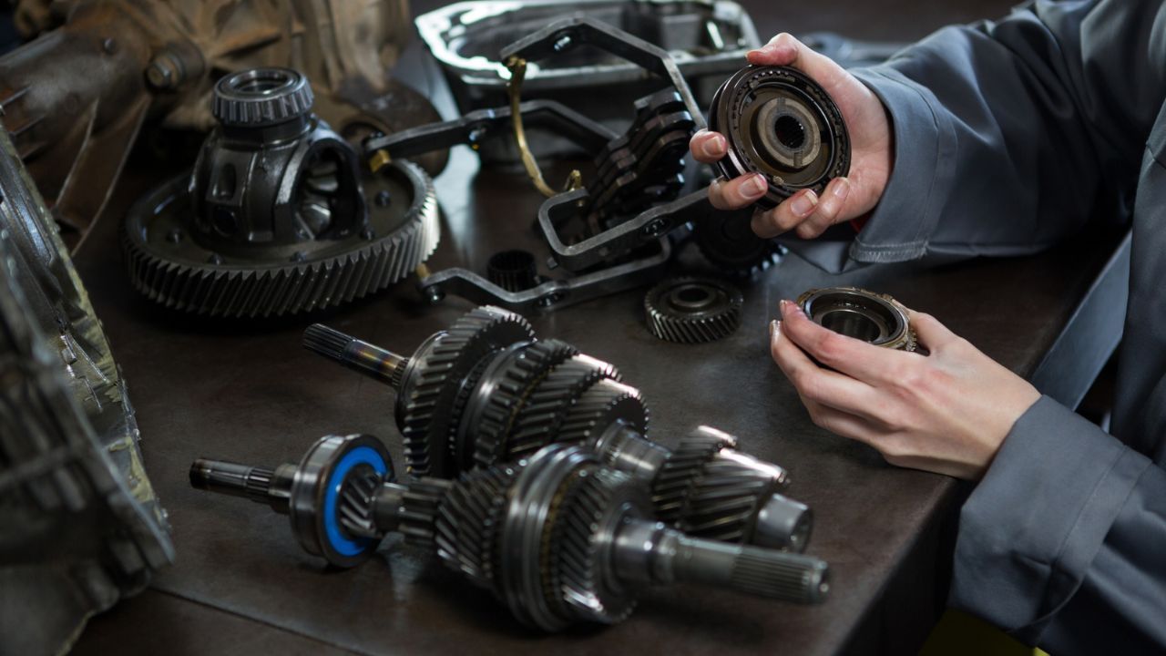 Automotive technician inspecting transmission gears and bearings during a transmission repair and diagnostic service.