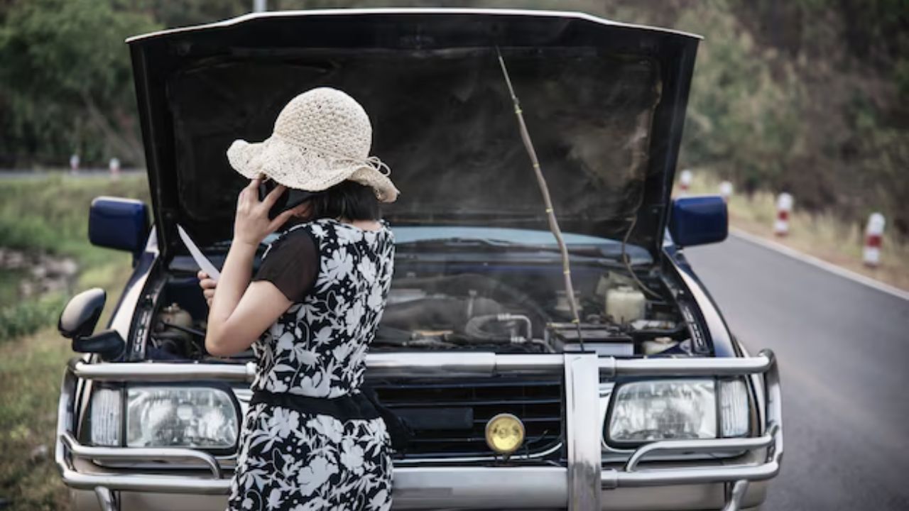 A woman standing in front of a car with the hood open and smoke coming out.
