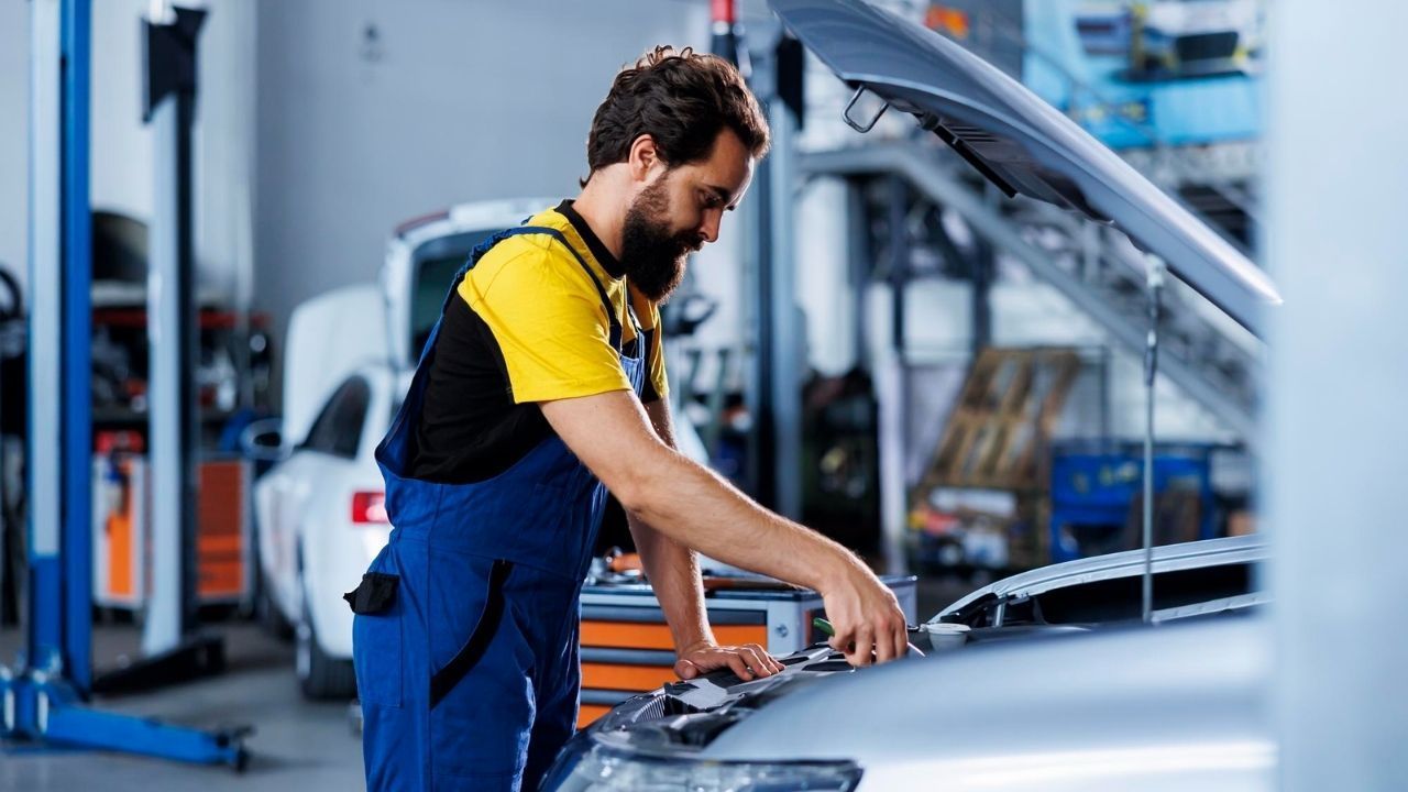 Professional mechanic inspecting a car engine in an auto repair shop.
