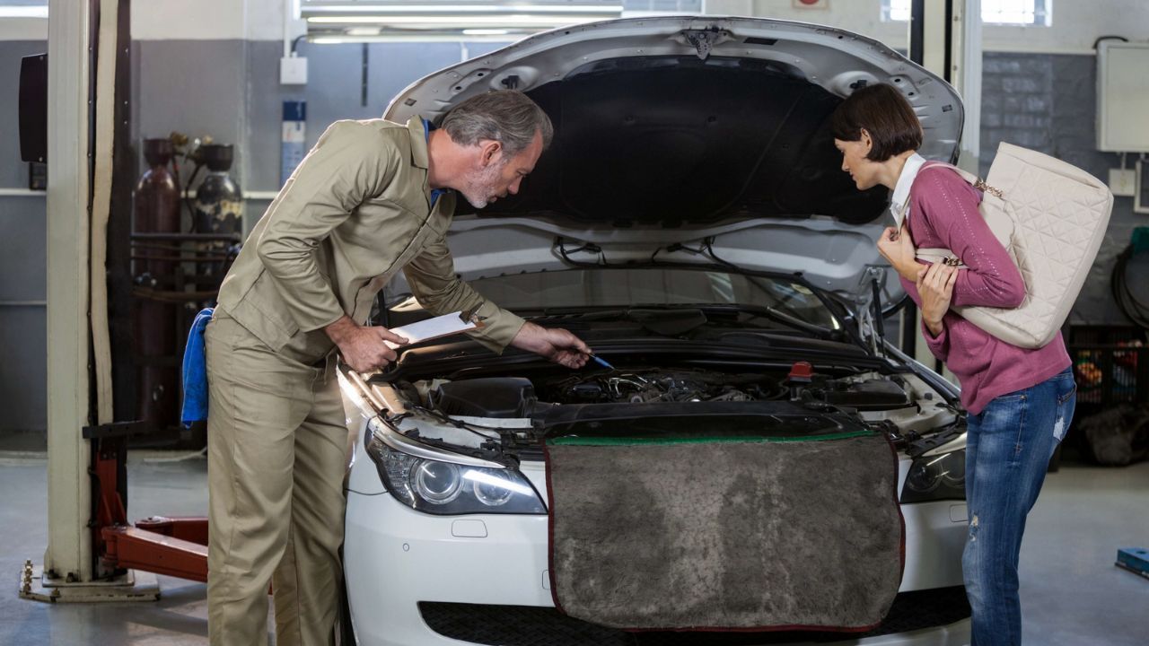 Mechanic explaining engine repair problem to car owner in auto repair shop
