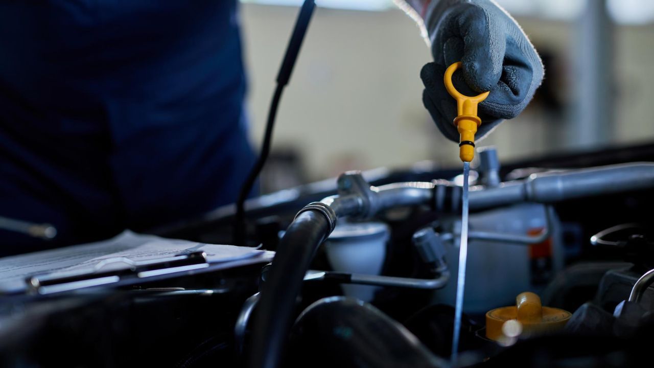 Technician measuring engine oil level with dipstick during inspection