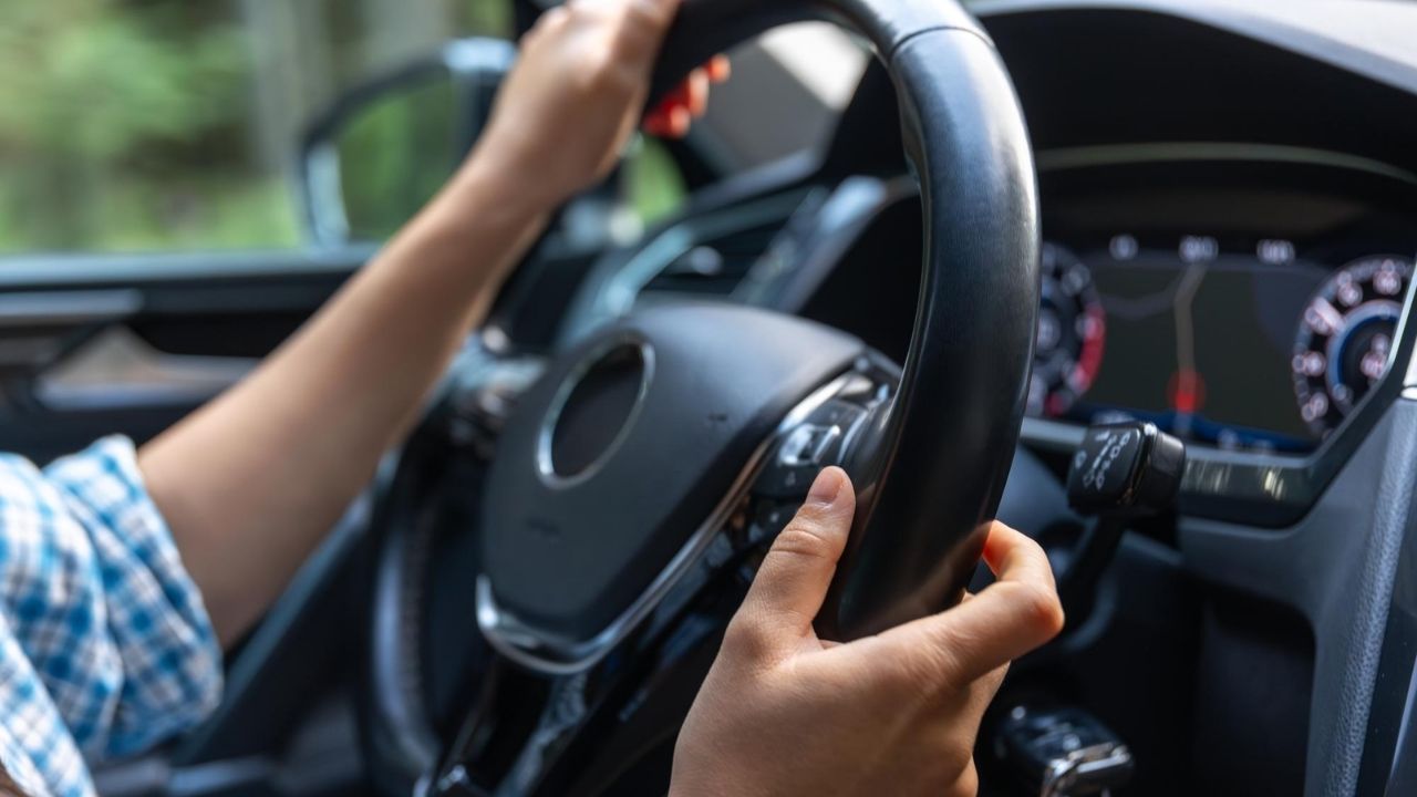Driver holding the steering wheel while checking vehicle handling and alignment.
