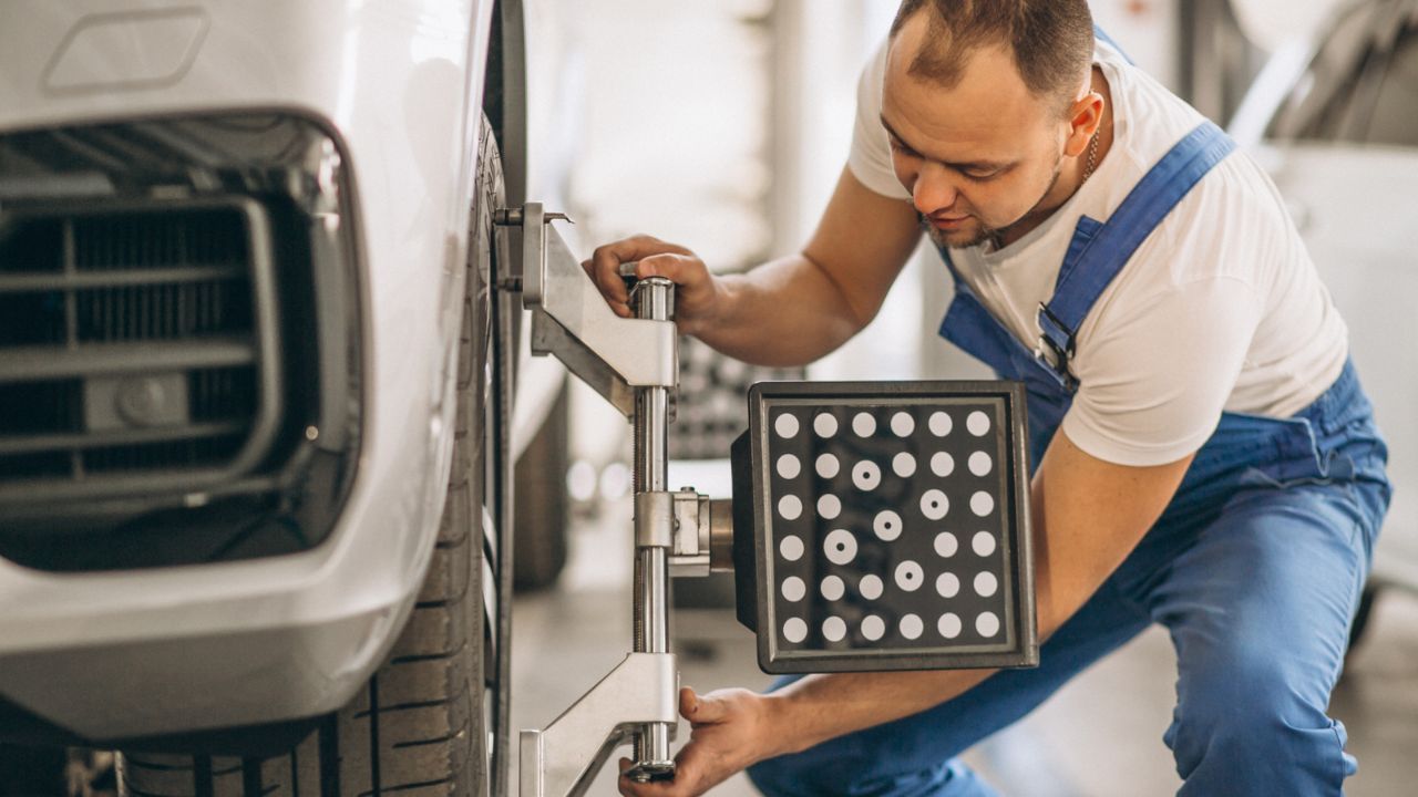 Automotive technician performing a wheel alignment service on a vehicle