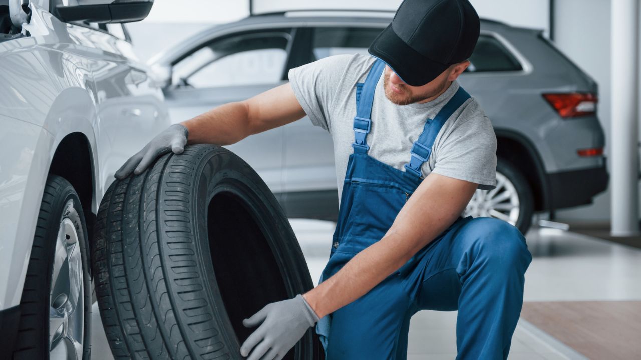  Mechanic checking tire condition beside a vehicle in a service center