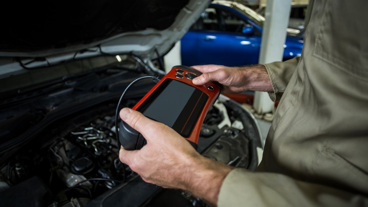 Auto technician using a diagnostic scanner to identify engine faults and troubleshoot vehicle performance issues.