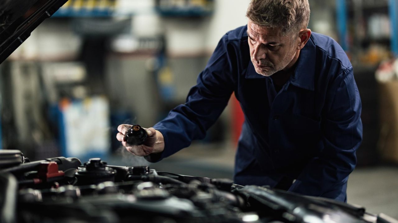 Auto technician checking coolant and engine components during vehicle maintenance service
