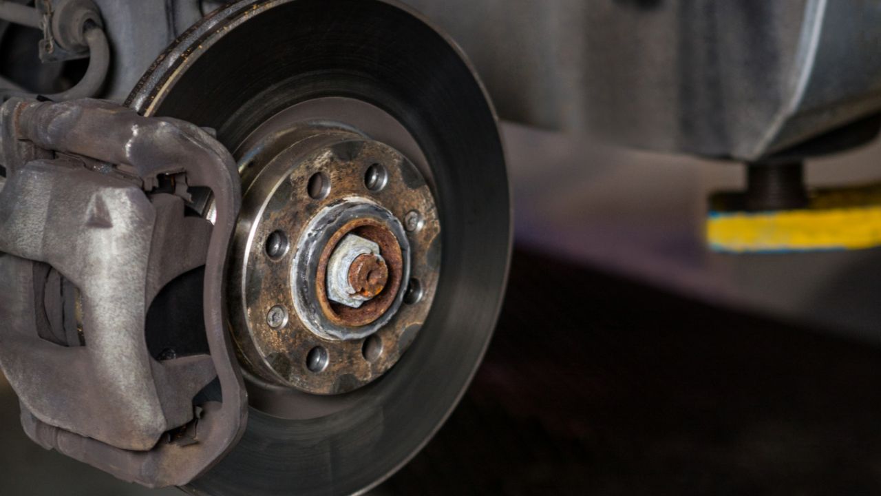 Close-up of a vehicle brake rotor and brake caliper during a brake inspection and maintenance service.