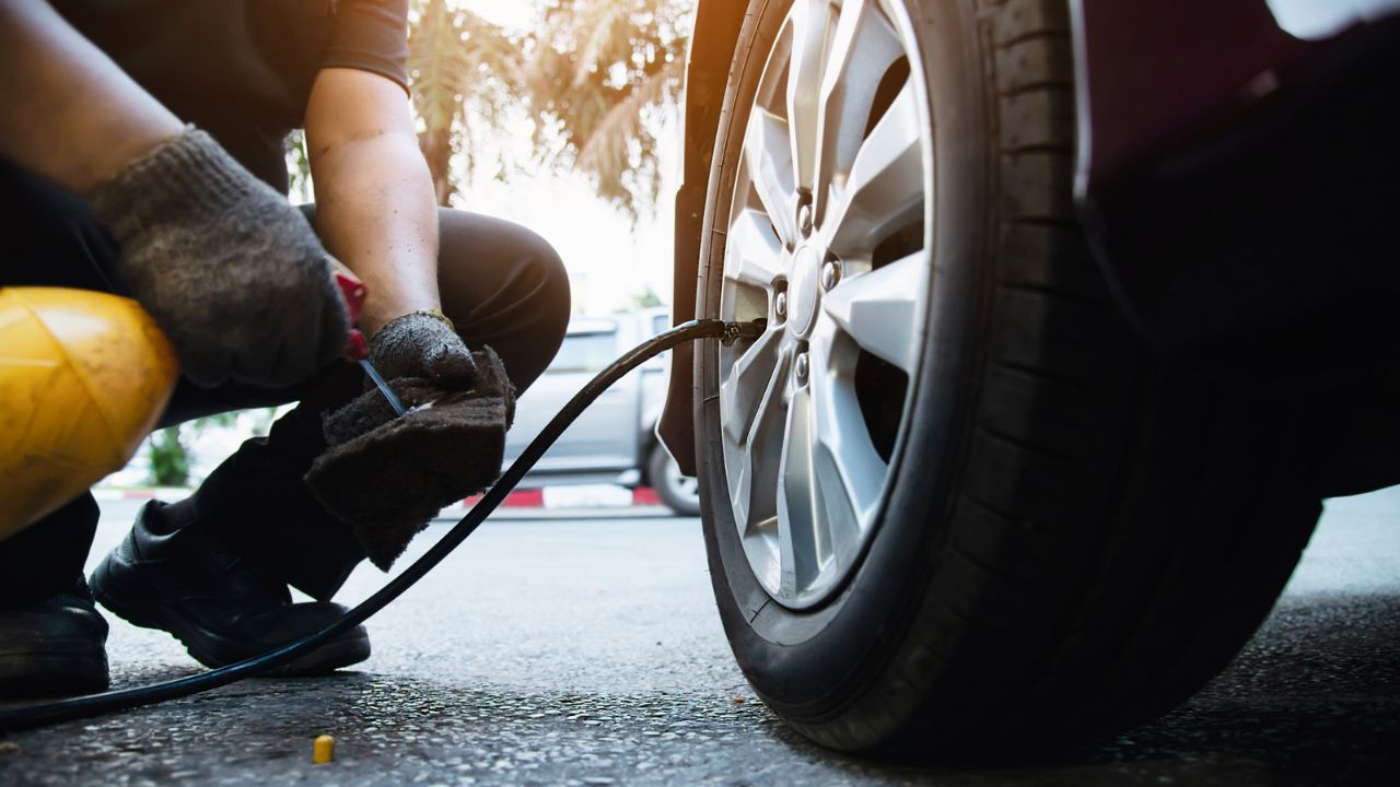 Technician checking and inflating a vehicle tire with an air hose