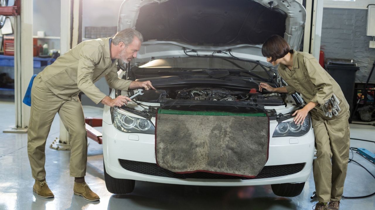 Auto repair technicians inspecting engine components during vehicle maintenance service