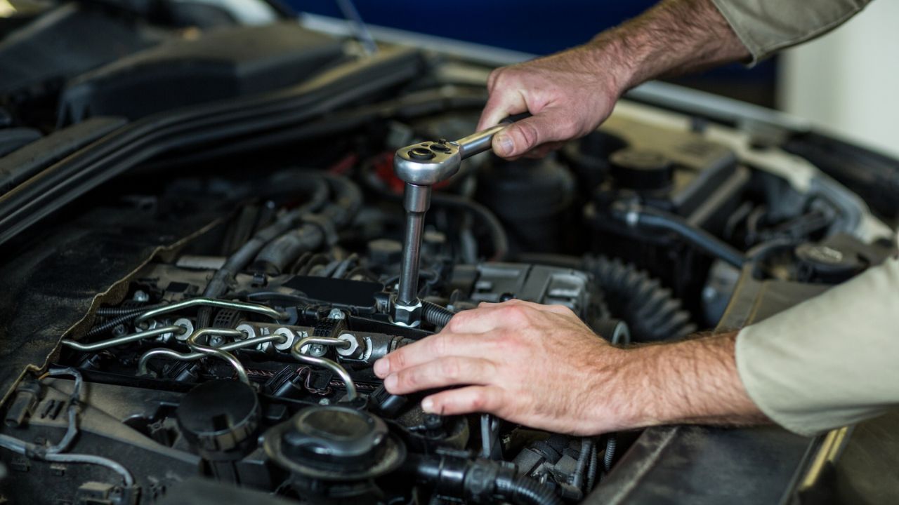 Auto technician using a ratchet tool to repair a car engine.  
