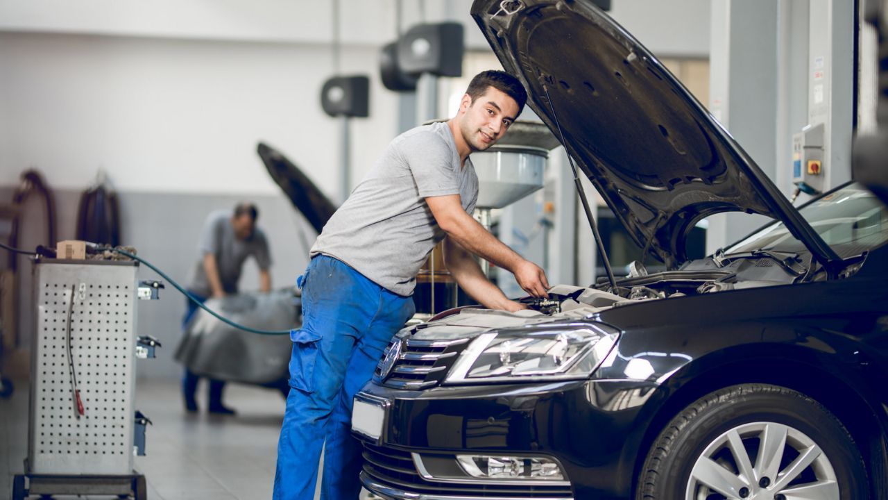 Automotive technician performing routine maintenance on a car in a garage.
