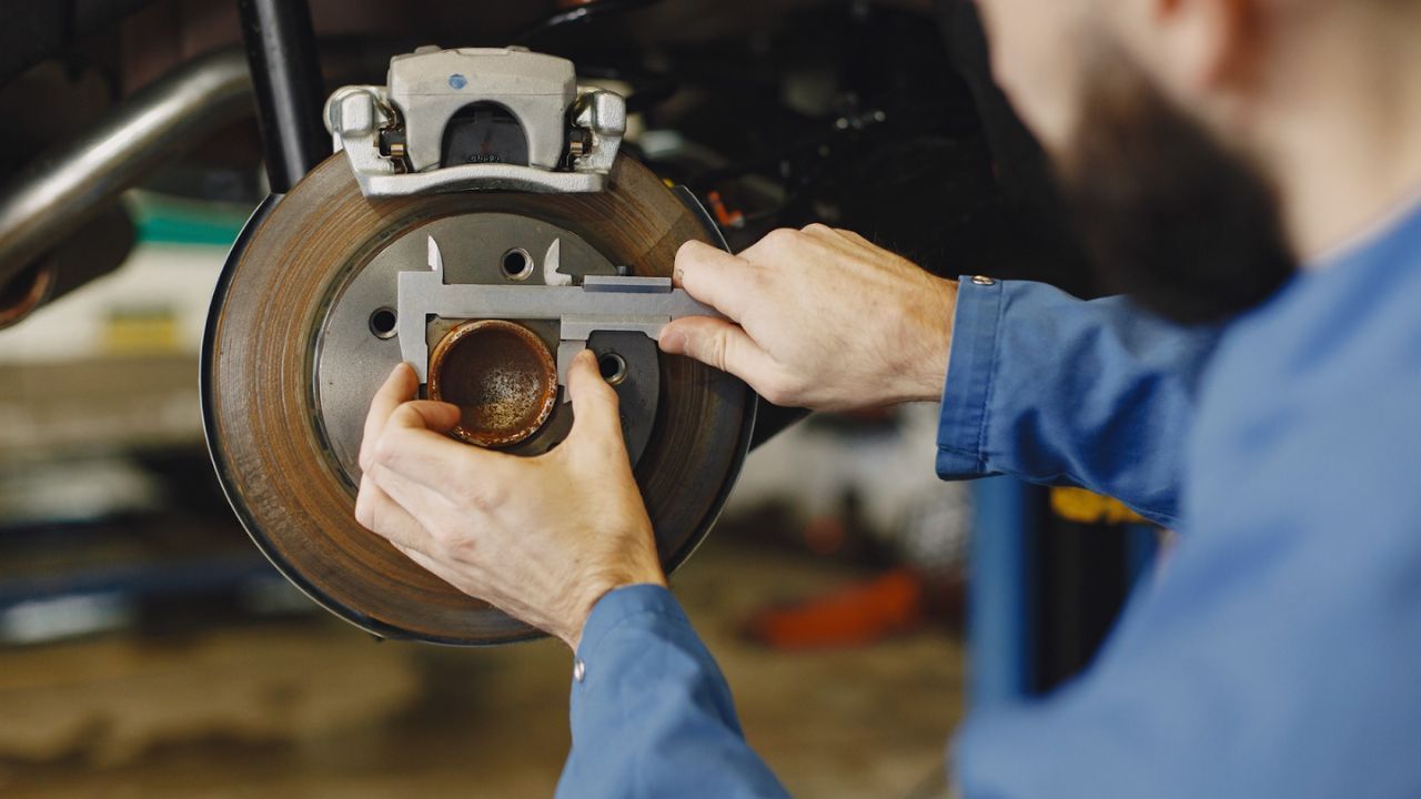 Mechanic checking wheel bearing wear during a car brake service.