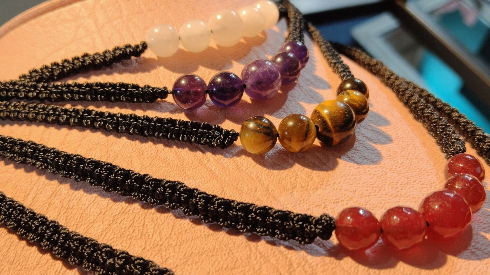 Collares coloridos de cuentas negras, blancas, moradas, doradas y rojas sobre una mesa