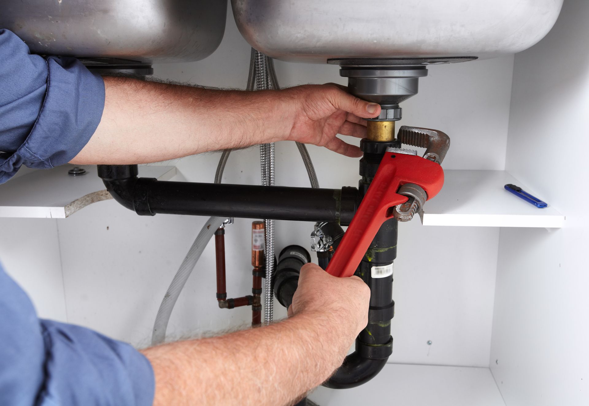 Hands of professional Plumber with a wrench. Clogged sink.