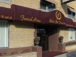 Maroon awning over a brick funeral home entrance with gold lettering and a crest sign