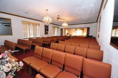 Empty church sanctuary with rows of brown chairs, chandeliers, and a pulpit at the front