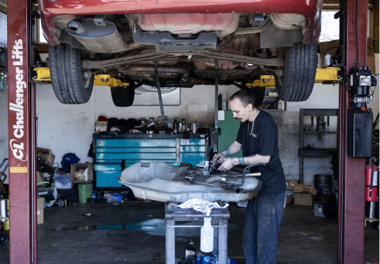 Mechanic working under a red car on a lift in an auto repair garage | Endurance Auto Repair and Tire