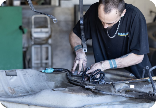 Worker using a power tool on a car body in a workshop | Endurance Auto Repair and Tire