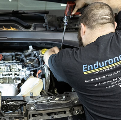 Mechanic using a power tool to repair a car engine in a garage | Endurance Auto Repair and Tire