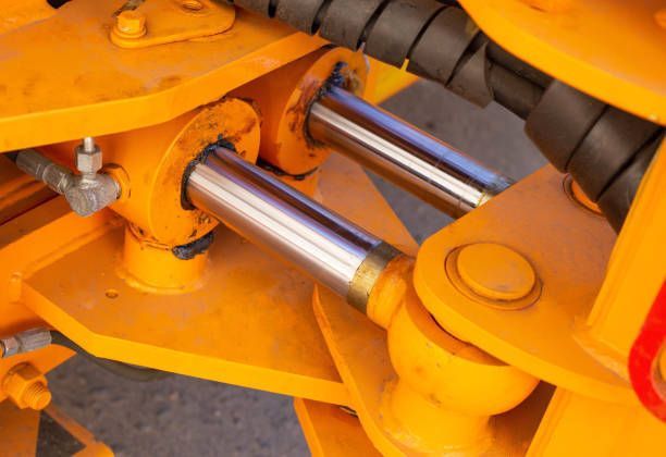 A close up of a hydraulic system on a yellow vehicle.