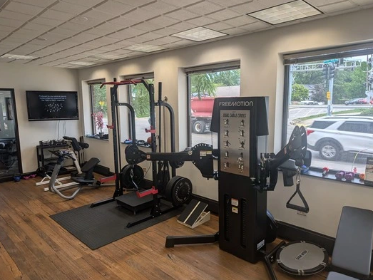 A gym with a lot of equipment and a lot of windows.