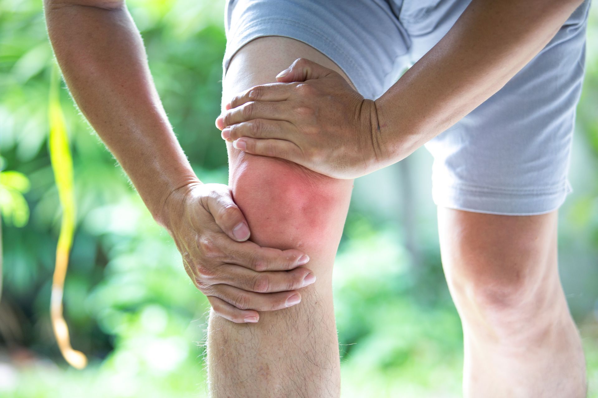 A man is holding his knee in pain.
