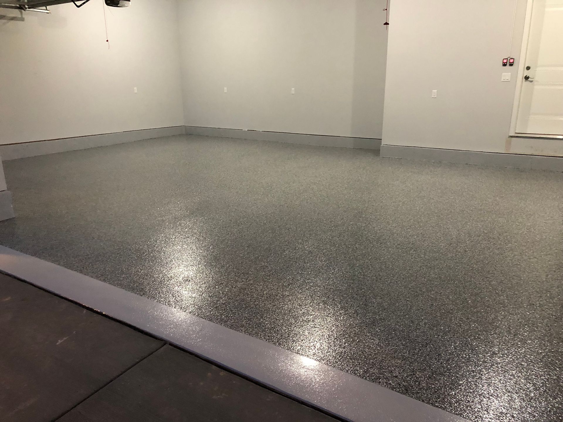 Empty gray garage with a speckled epoxy floor and white walls