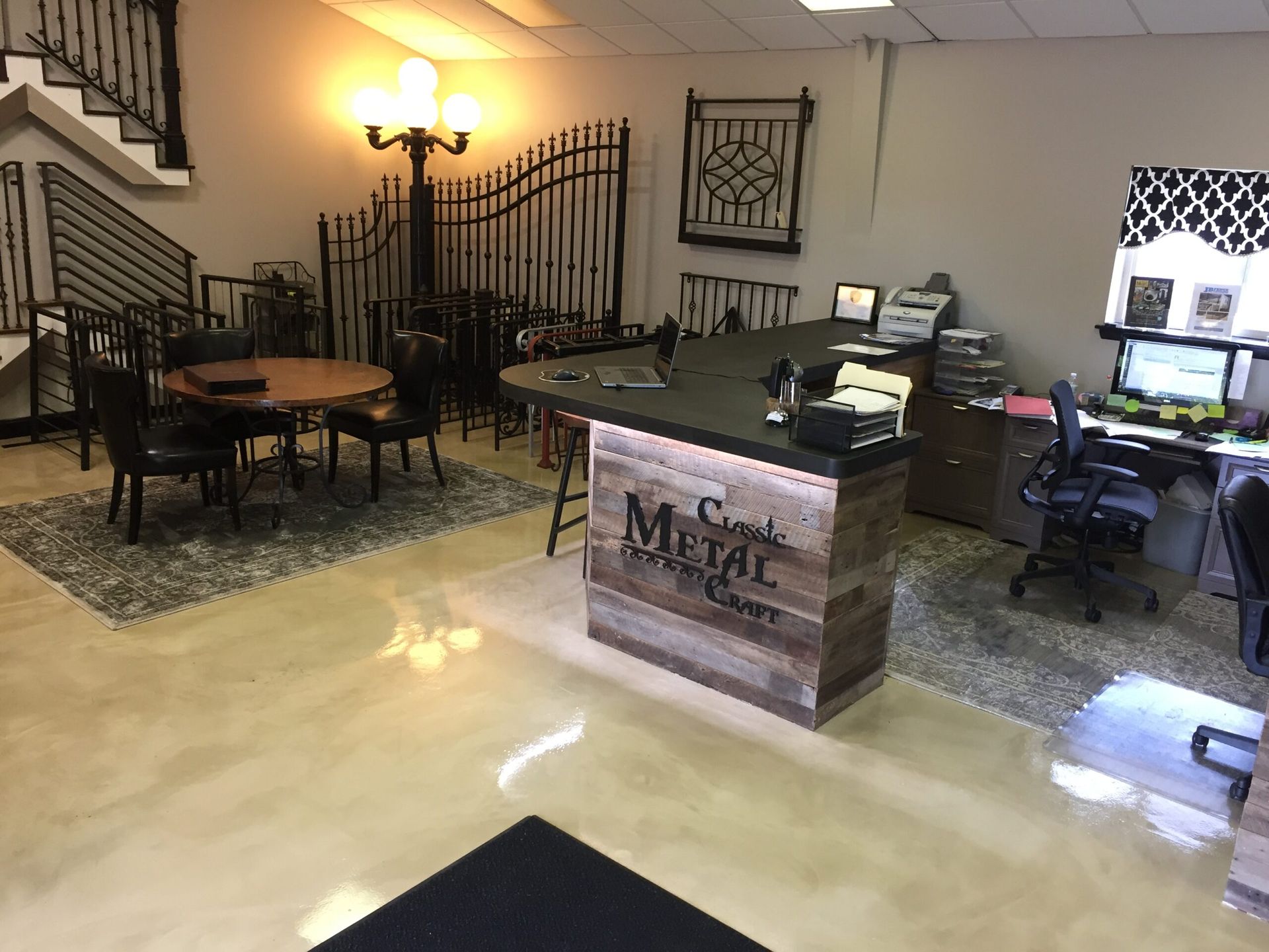 Hotel lobby with reception desk, seating area, wrought-iron decor, and warm wall lighting.