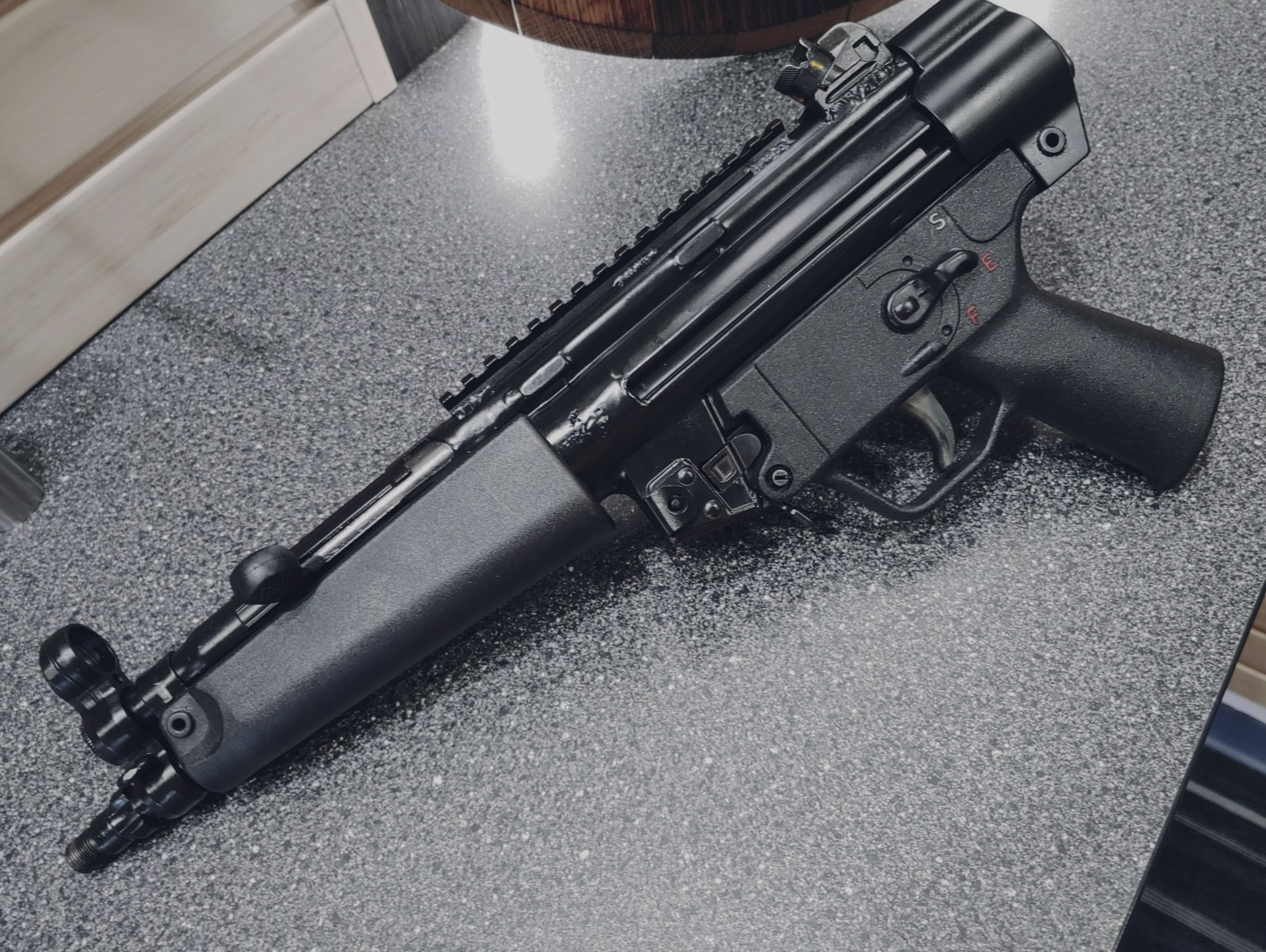 Black submachine gun on a speckled countertop.