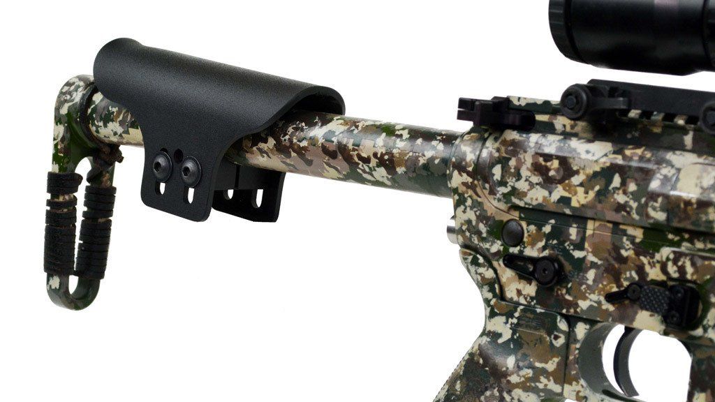 Close-up of a camouflage-painted rifle with a black cheek rest and scope.