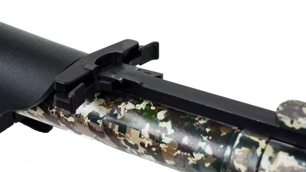Close-up of a rifle barrel with a camouflage pattern and black metal parts, likely the bolt assembly.