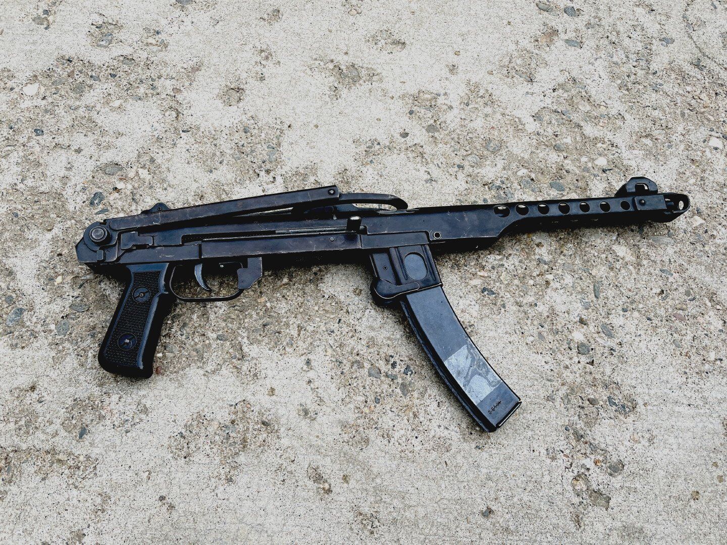 Black PPSh-41 submachine gun on a concrete surface.