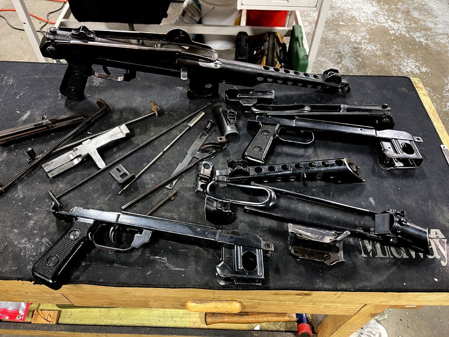 Disassembled black firearm parts on a workbench.