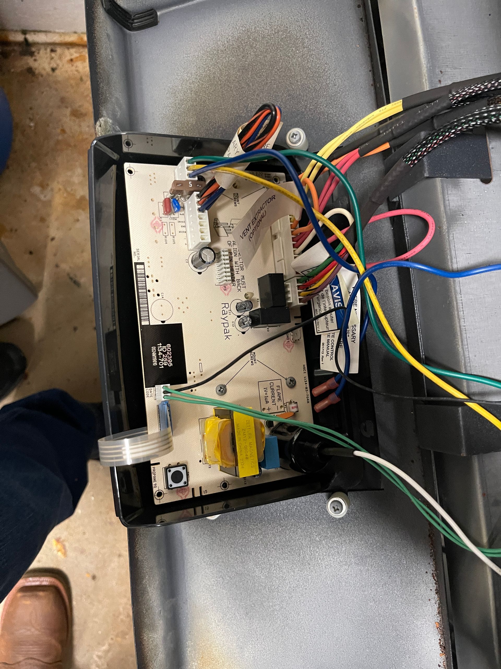 Circuit board with various colored wires and electronic components, inside a metal frame.