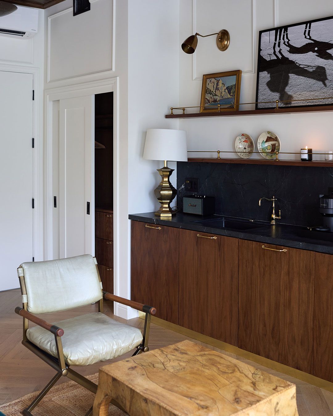 Living room corner with midcentury chair, wooden cabinet, lamp, and framed artwork