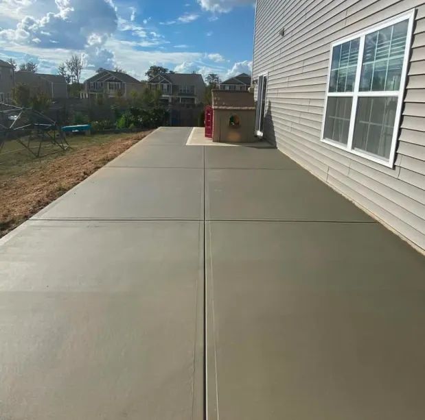 A concrete patio with a grill in the backyard of a house