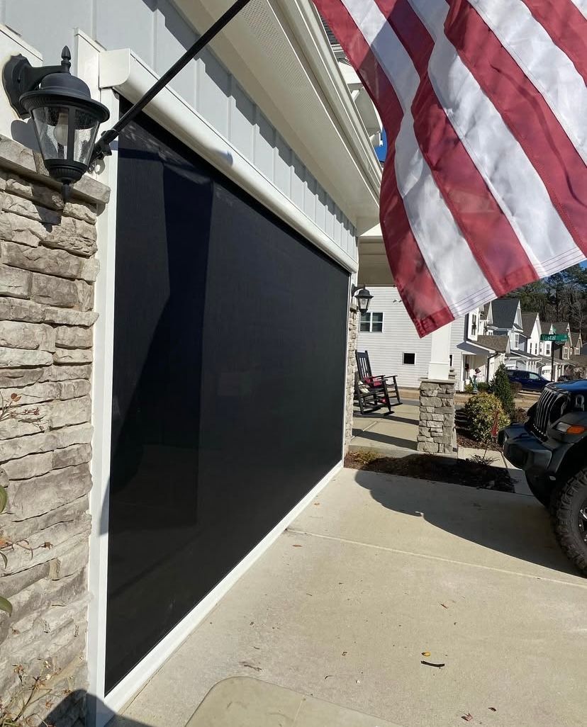 An american flag is flying in front of a black garage door