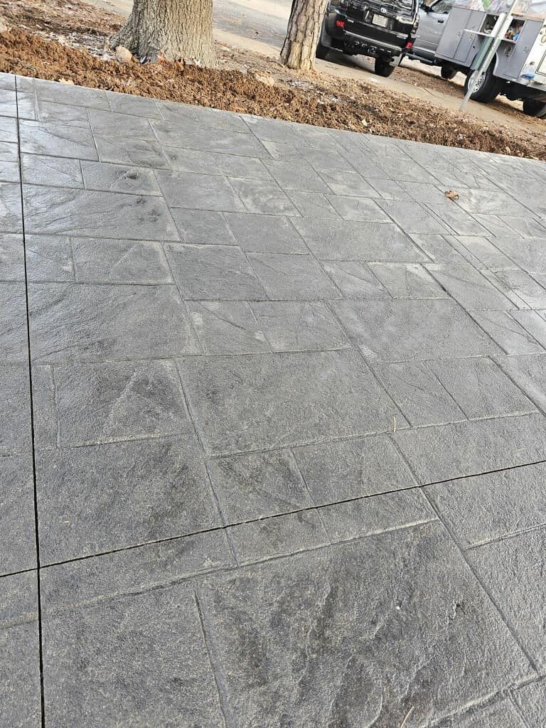 A gray tiled driveway with a truck parked in the background