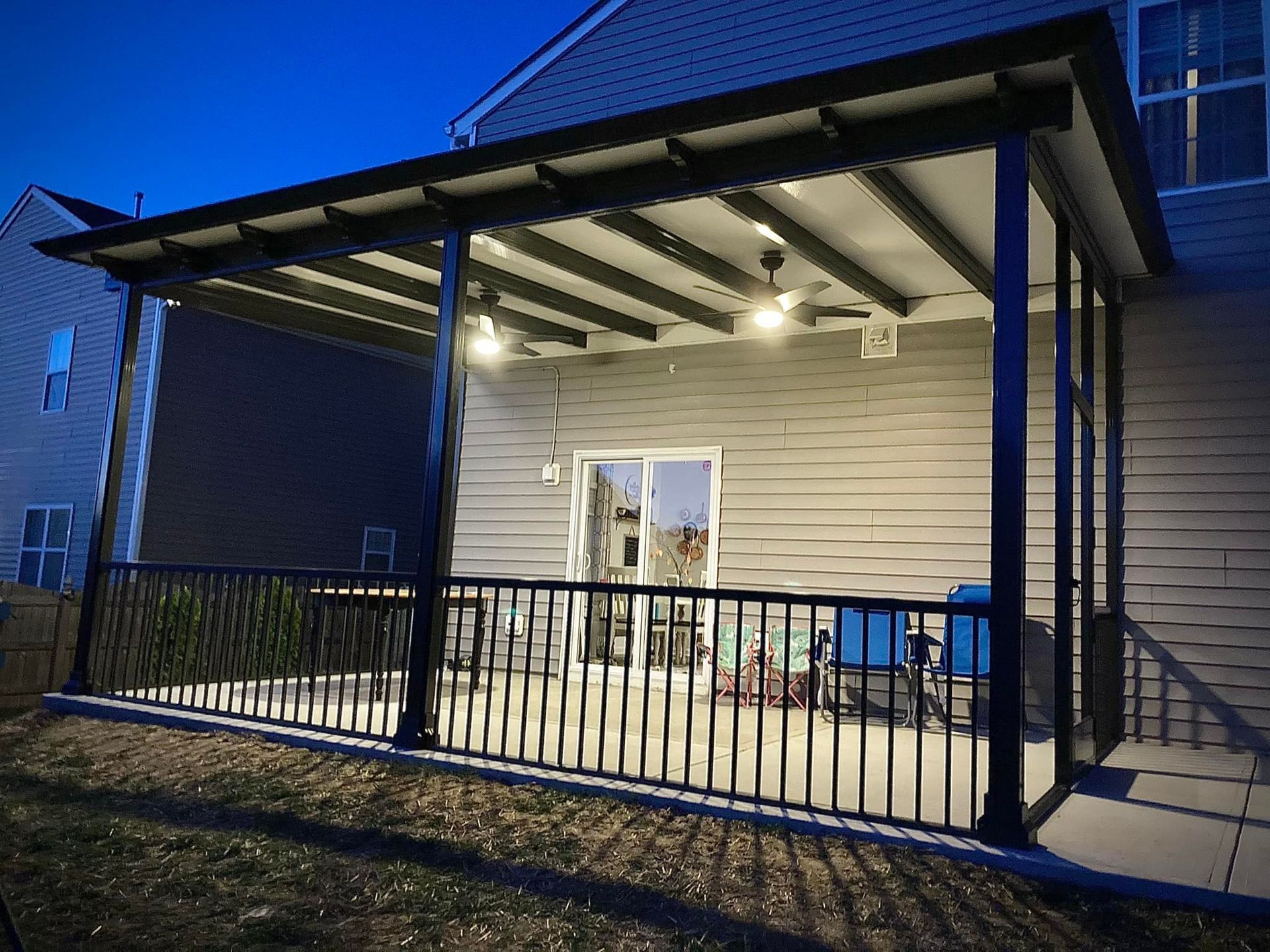 A porch with a railing and a ceiling fan is in the backyard of a house