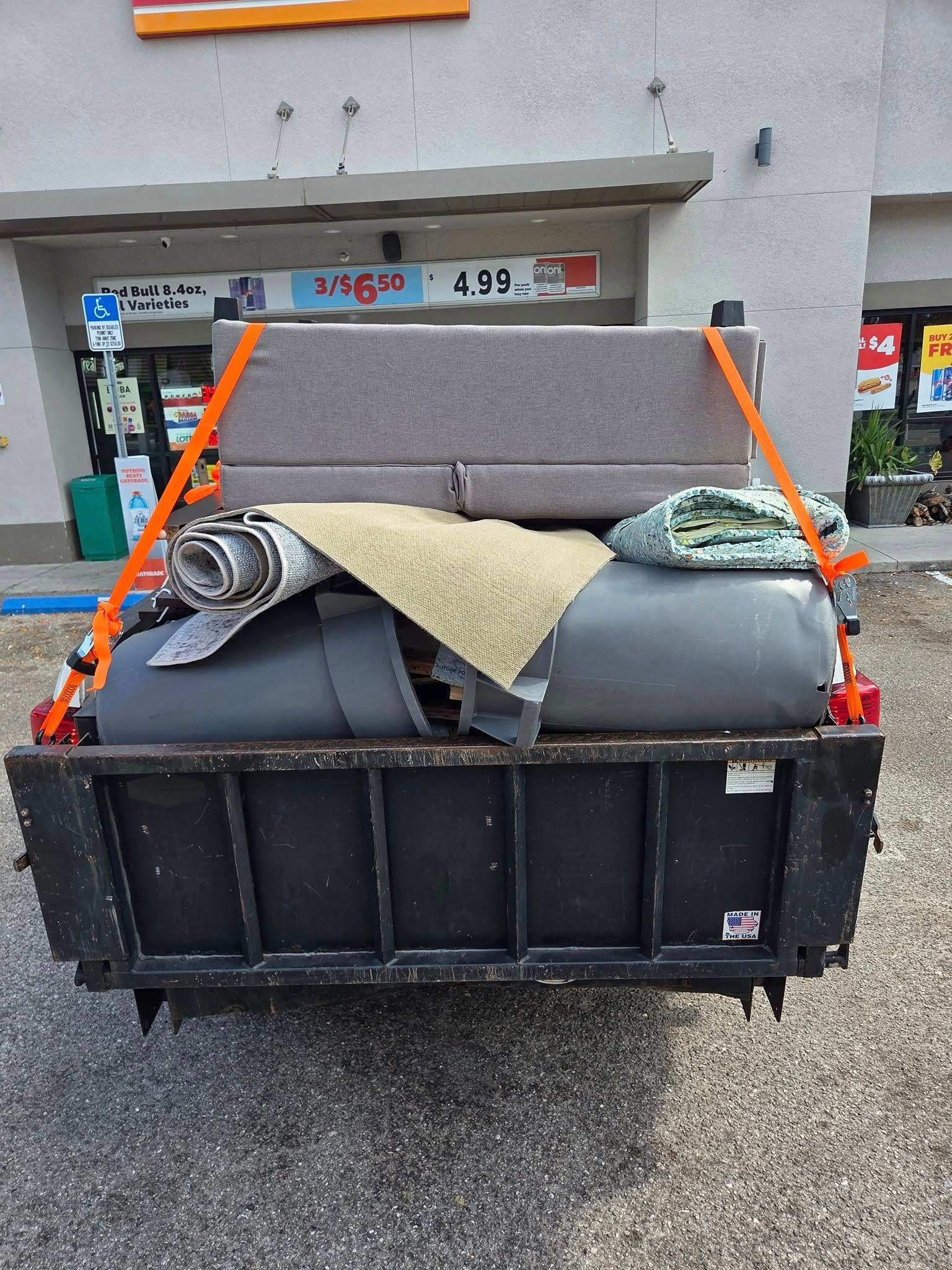 Dumpster filled with discarded rugs and debris outside a storefront