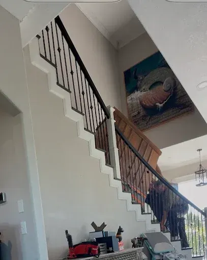 Staircase with black iron railing and wall art in a bright home foyer