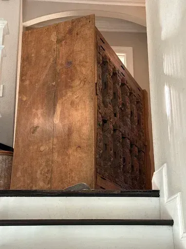 Large brown upholstered chair wedged sideways on a narrow staircase landing between white walls