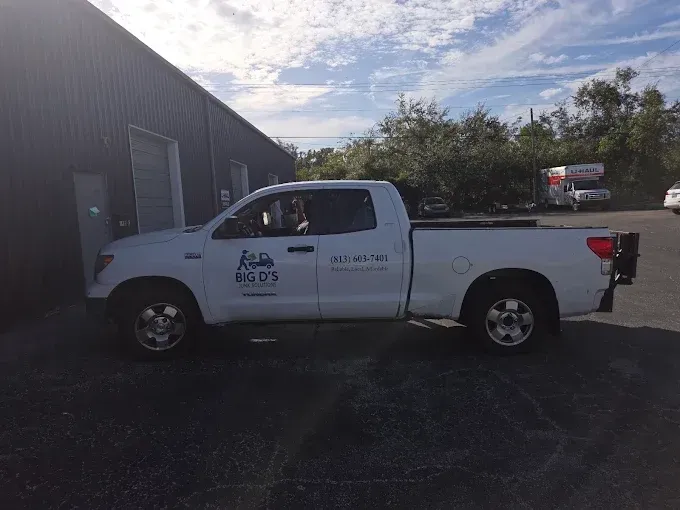 White utility pickup truck parked beside a building on a sunny day
