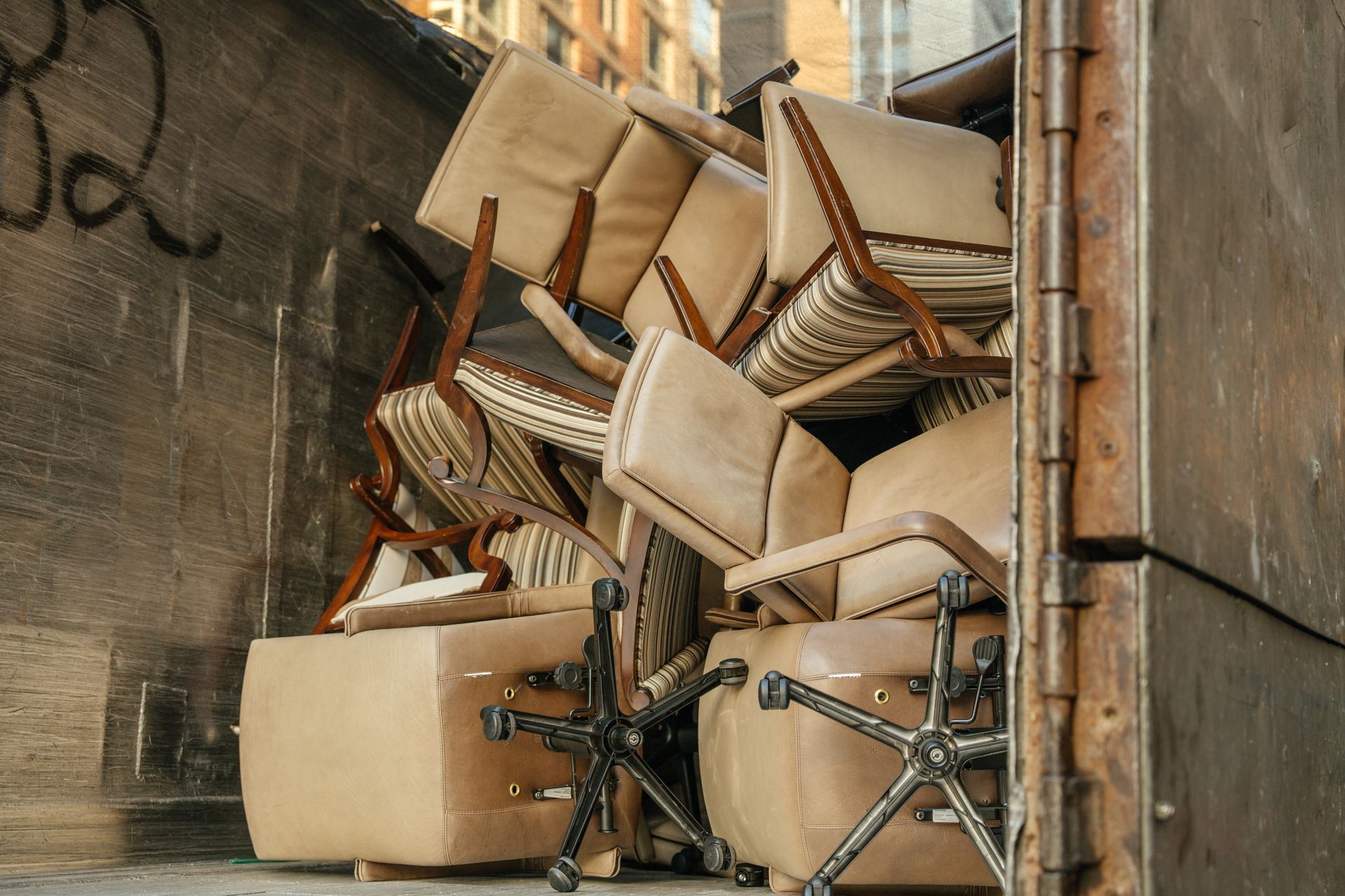 Stacked chairs and tables spilling over in a narrow alley beside a brick wall