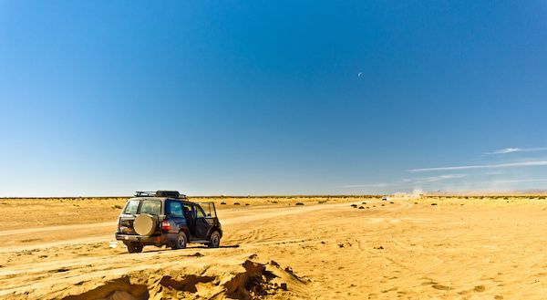 SUV on a sandy desert track under a clear blue sky