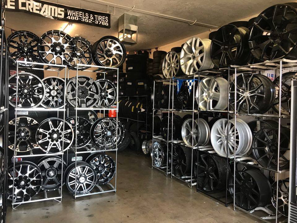 Shelves stacked with black and silver car rims in a tire shop showroom
