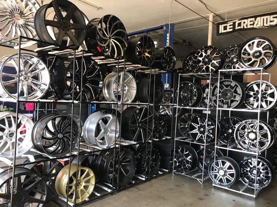 Shelves stacked with assorted car rims and wheels in a tire shop or showroom