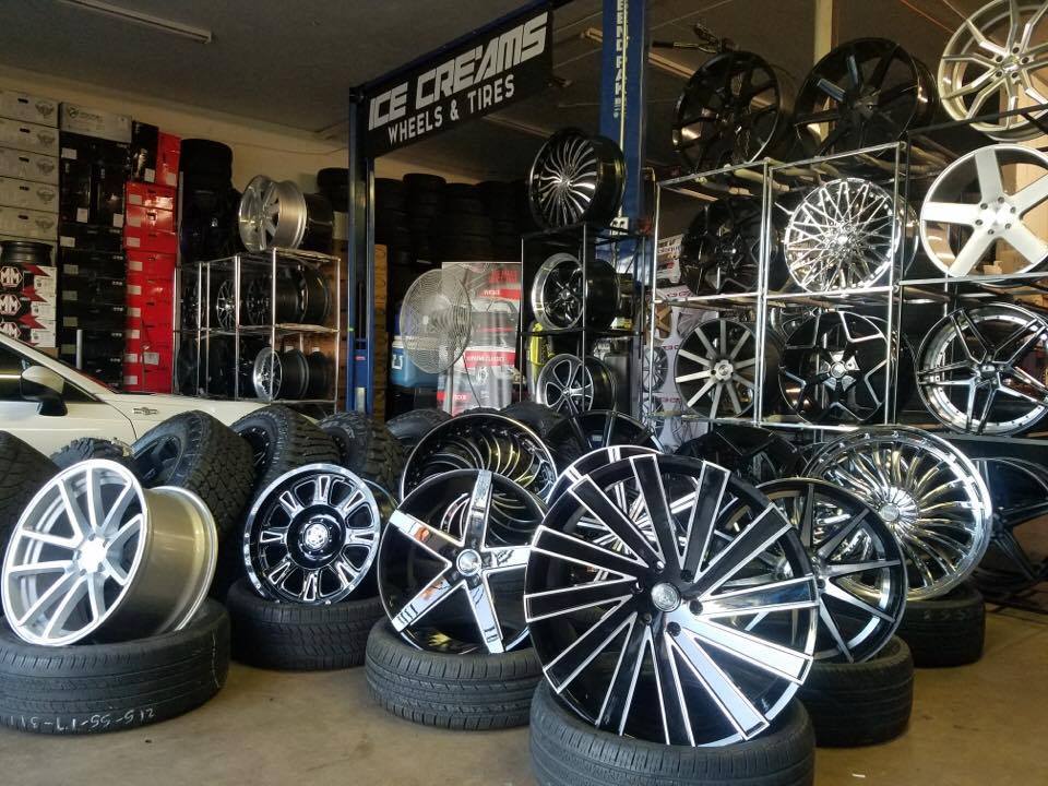 Tire shop display with shiny custom car rims and wheels on shelves and stacked on the floor