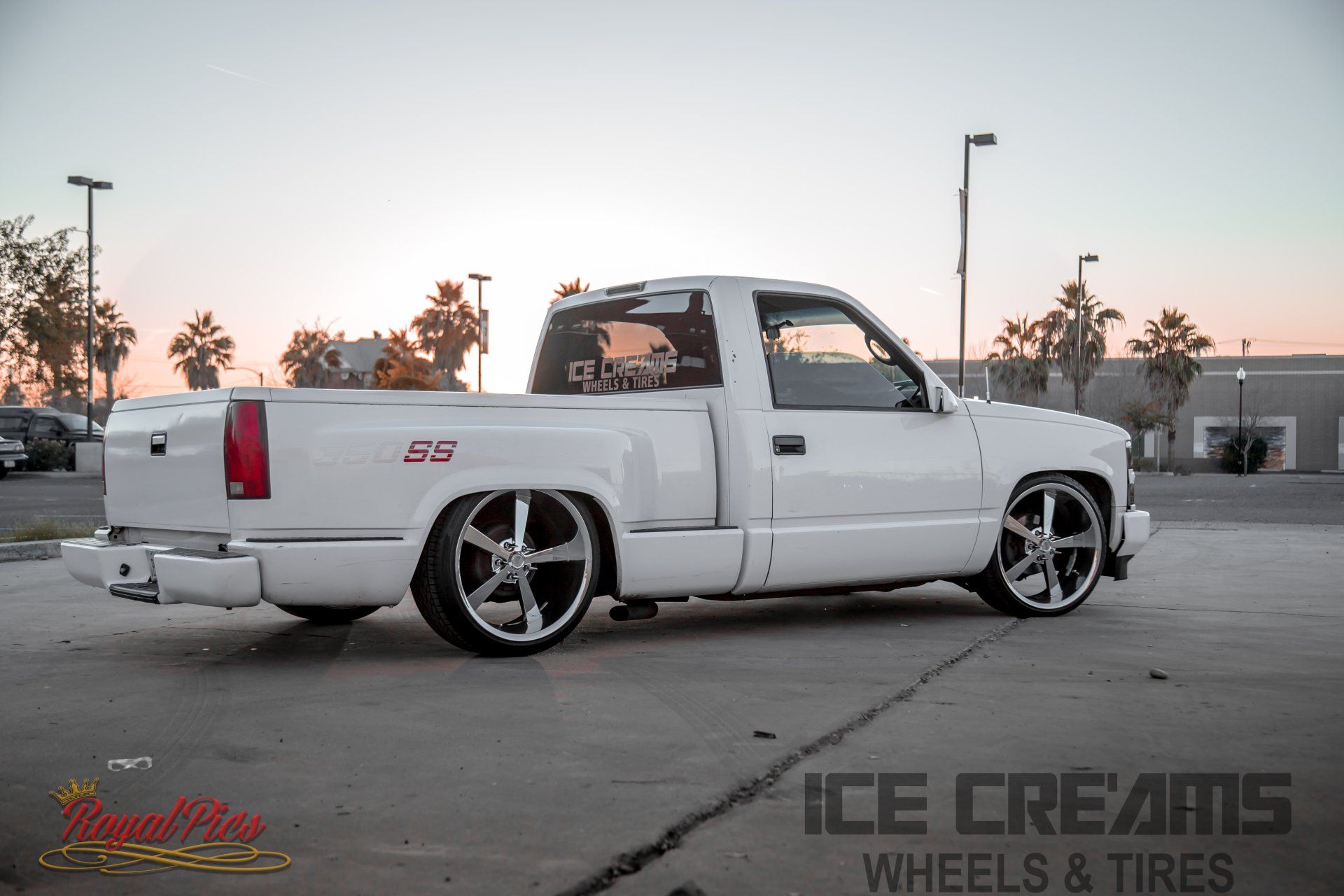 Lowered white pickup truck with chrome rims parked at dusk in a lot